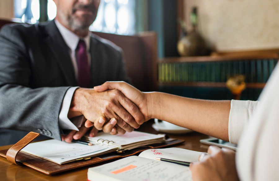 Attorney shaking hands with a client at their desk